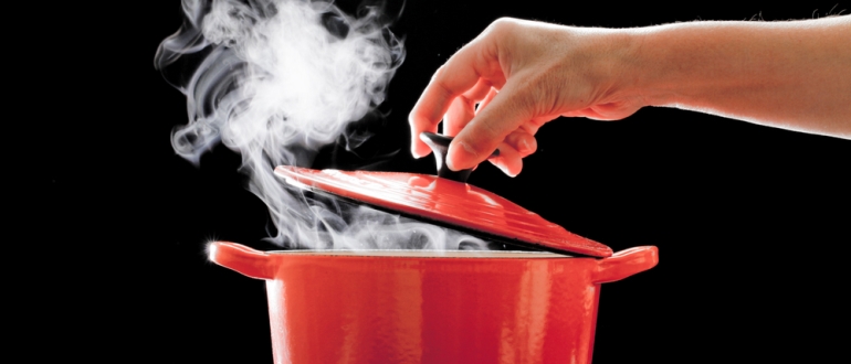 the hand opens the lid of the pot of boiling water